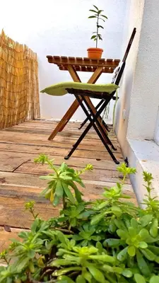 a wooden table and chair on a porch with a plant at Bonaca Apartments in Budva