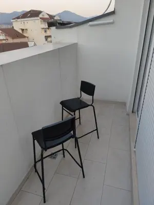 two chairs on a balcony with a view of a city at Blue Apartment Riverside in Podgorica