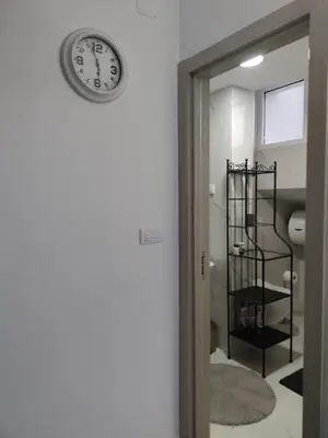 a clock on a wall next to a bathroom at Blue Apartment Riverside in Podgorica