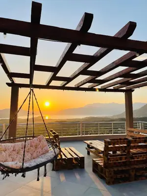 a porch with a swing with the sunset in the background at Sunset Apartments in Kotor