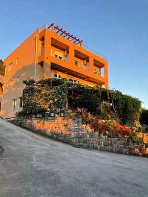 an orange building with flowers on a stone wall at Sunset Apartments in Kotor