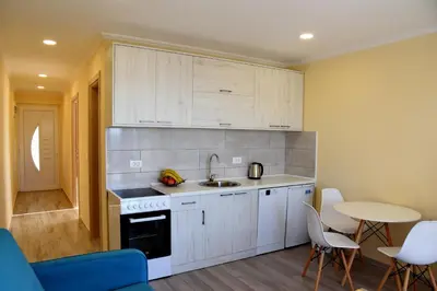 a kitchen with white cabinets and a sink and a table at Sunset Apartments in Kotor