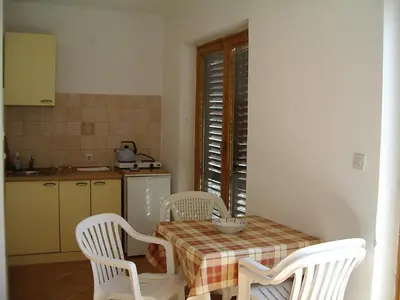 a kitchen with a table and two chairs and a table and a kitchen at Guest house Živković in Sveti Stefan