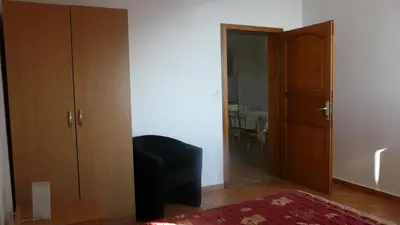 a bedroom with a closet and a chair and a door at Guest house Živković in Sveti Stefan