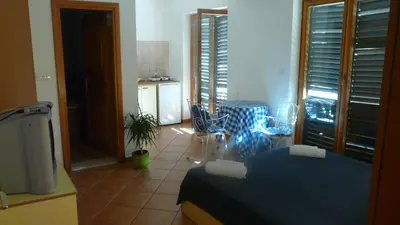 a room with a bed and a kitchen with a table at Guest house Živković in Sveti Stefan