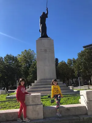 two little girls standing in front of a statue at Apartmani Vila in Cetinje