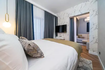 a hotel room with a white bed and a living room at Hotel Millennium by Aycon in Budva