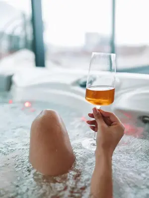 a person holding a glass of beer in a bathtub at Hotel Millennium by Aycon in Budva