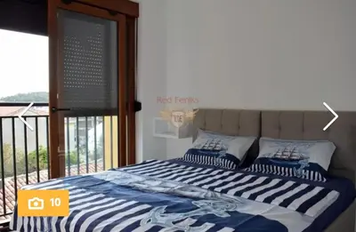 a bed with blue and white sheets and a balcony at Apartman Pejovic in Petrovac na Moru