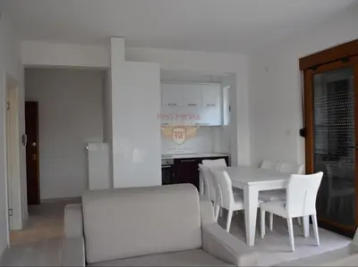 a dining room with a white table and white chairs at Apartman Pejovic in Petrovac na Moru