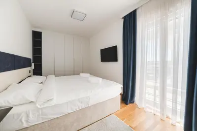 a bedroom with a white bed and a large window at Fontana Residence Budva in Budva