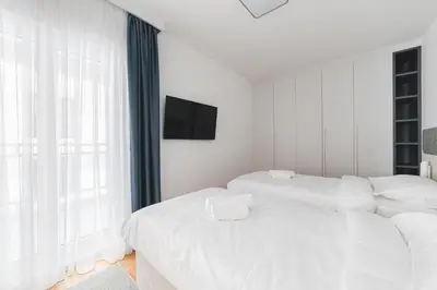 a white bedroom with two beds and a tv at Fontana Residence Budva in Budva