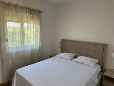 a bedroom with a bed with white sheets and a window at Niki Apartments in Ulcinj