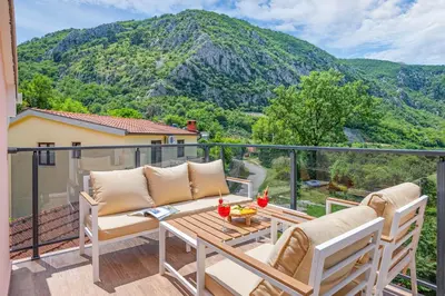 a balcony with a table and chairs and a mountain at Apartment Petar 2 in Kotor