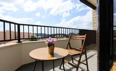 a table and chairs on a balcony with a vase of flowers at Sea view apartment in Becici in Budva