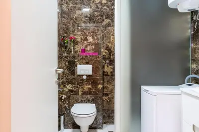 a bathroom with a toilet and a stone wall at Tre Canne Red Bull in Budva