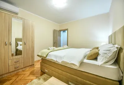 a bedroom with a large bed and a mirror at Apartman Centar 2 in Podgorica