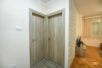 a wooden door in a room with a brick wall at Apartman Centar 2 in Podgorica