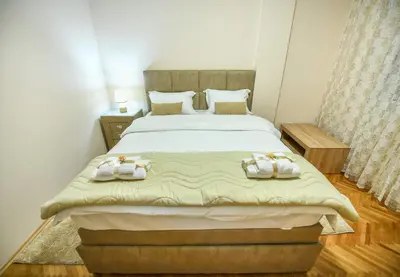 a bedroom with a large bed with towels on it at Apartman Centar 2 in Podgorica