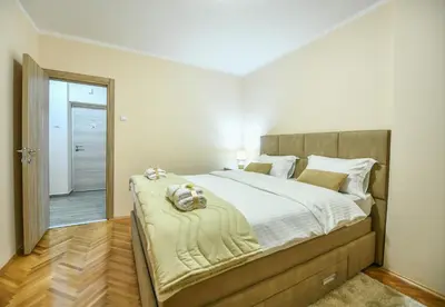 a bedroom with a large bed and a mirror at Apartman Centar 2 in Podgorica