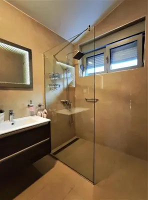 a bathroom with a glass shower and a sink at Pavlina Apartments Budva in Budva