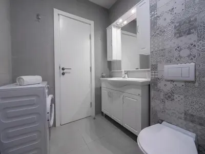 a white bathroom with a toilet and a sink at Marea Apartments Budva in Budva