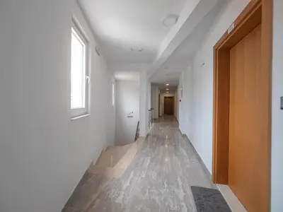 a hallway with white walls and a wooden door at Marea Apartments Budva in Budva