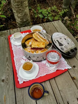 a picnic table with a pan of food and two cups of sauce at Breeze Home Cottage in Cetinje