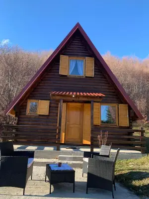 a log cabin with chairs and a table in front of it at Breeze Home Cottage in Cetinje