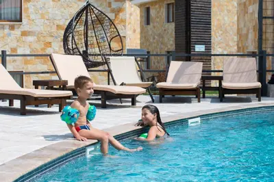 a boy and a girl sitting in a swimming pool at Ethno Village St George in Cetinje