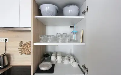 a kitchen with white dishes and bowls on shelves at Romantic sea view apartment in Petrovac in Petrovac na Moru