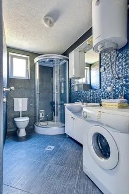 a bathroom with a shower and a washing machine at Apartment With a View in Budva
