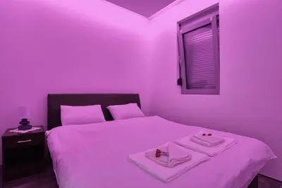 a purple room with a bed with two towels on it at Apartment With a View in Budva