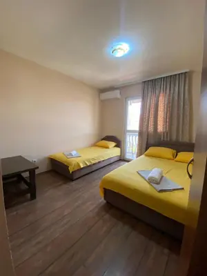 a room with two beds and a table and a window at Apartments and Rooms Grande Casa in Bar