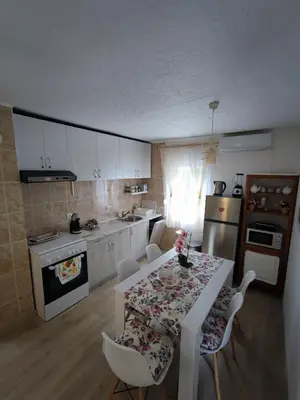 a kitchen with a table and chairs and a kitchen with white cabinets at Apartment Barba View in Kotor