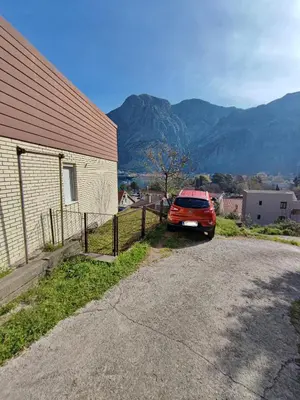 a car parked next to a building with mountains in the background at Apartment Barba View in Kotor