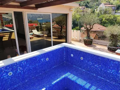 a blue swimming pool in front of a house at Villa Vista Real in Kotor