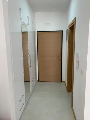 a hallway with white cabinets and a wooden door at Apartman A2 in Ulcinj
