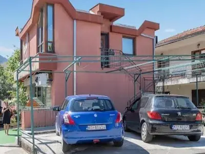 two cars parked in front of a pink building at Mila's studio in Kotor
