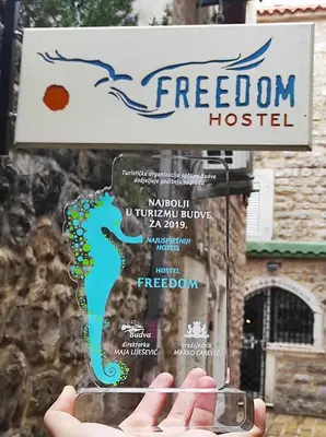 a person holding a sign that reads freedom hospital at FREEDOM HOSTEL in Budva