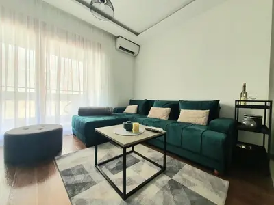 a living room with a green couch and a table at Apartman Ana Lux in Podgorica