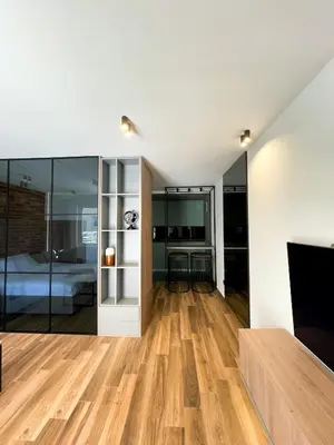 a bedroom with a bed and a living room with wood floors at Anja & Ogo apartments with Pool _ in Petrovac na Moru