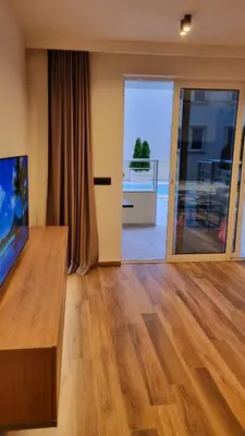 a living room with a tv and a wooden floor at Anja & Ogo apartments with Pool _ in Petrovac na Moru