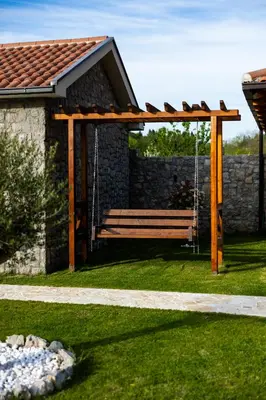 a wooden pergola with a bench in a yard at Lake Valley in Virpazar