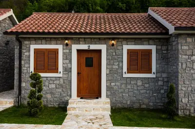 a small stone house with a brown door and windows at Lake Valley in Virpazar