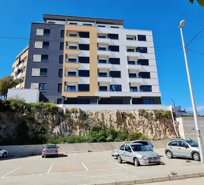 a tall building with cars parked in a parking lot at SeaView Apartment & Pool in Ulcinj
