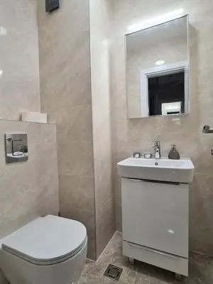 a bathroom with a toilet and a sink and a mirror at Green Apartments Podgorica With Garage in Podgorica