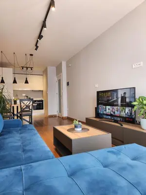 a living room with a blue couch and a table at Green Apartments Podgorica With Garage in Podgorica