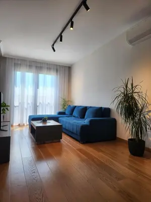 a living room with a blue couch and a table at Green Apartments Podgorica With Garage in Podgorica