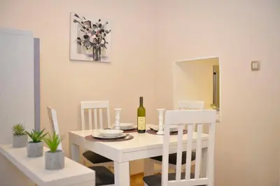 a white dining room with a white table and chairs at Apartment Filip in Kotor